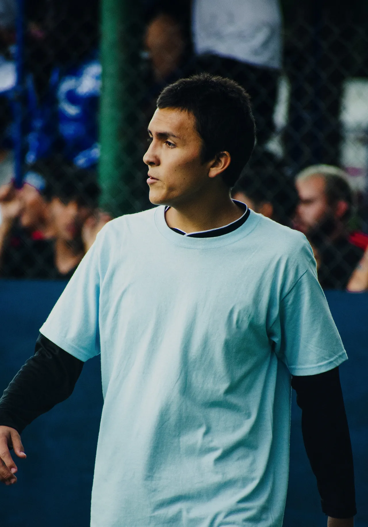 A player in the ice-blue away shirt over a black base layer, eyes on the play.
