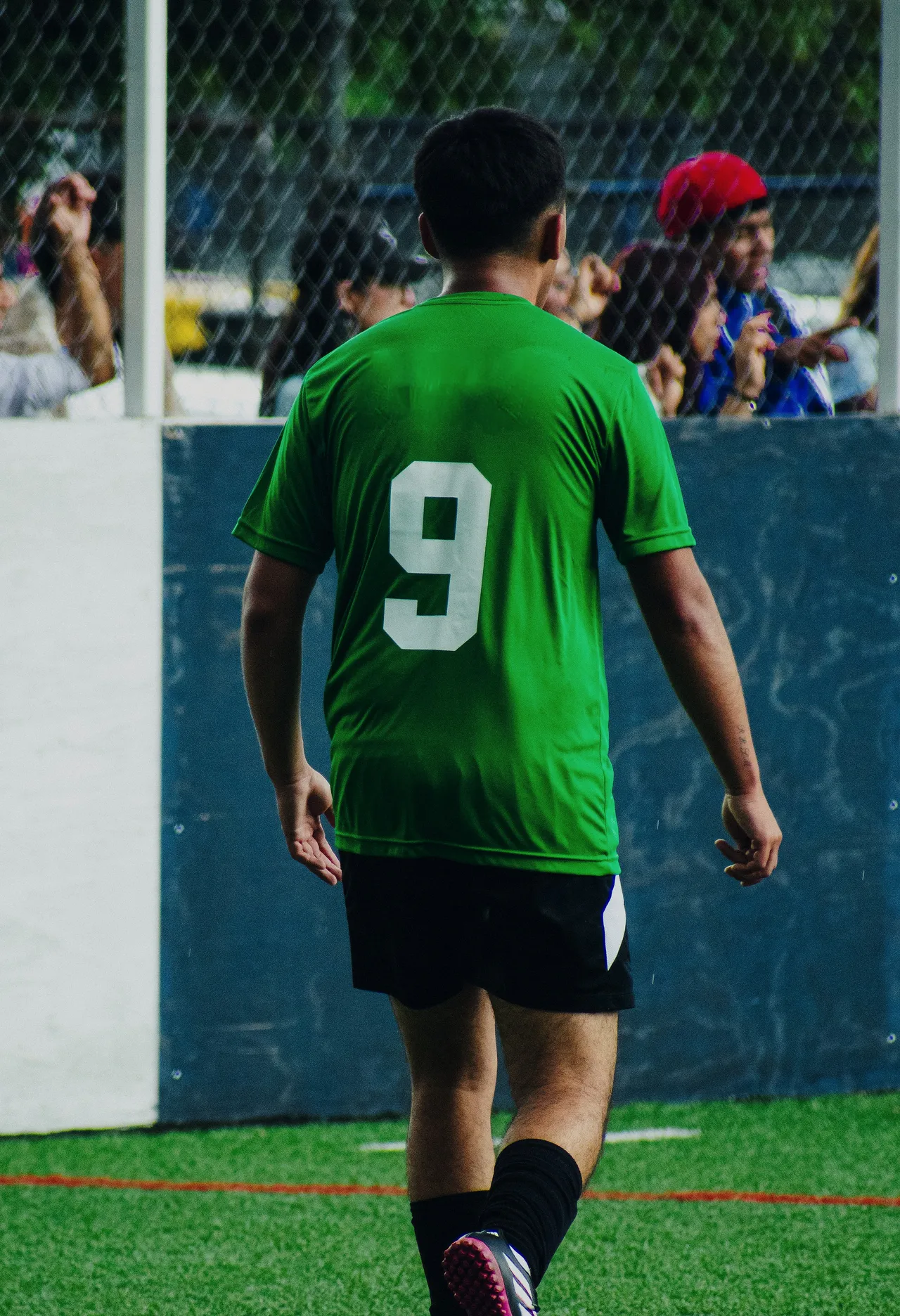 A player in the green home shirt, number 9, walking back to position.