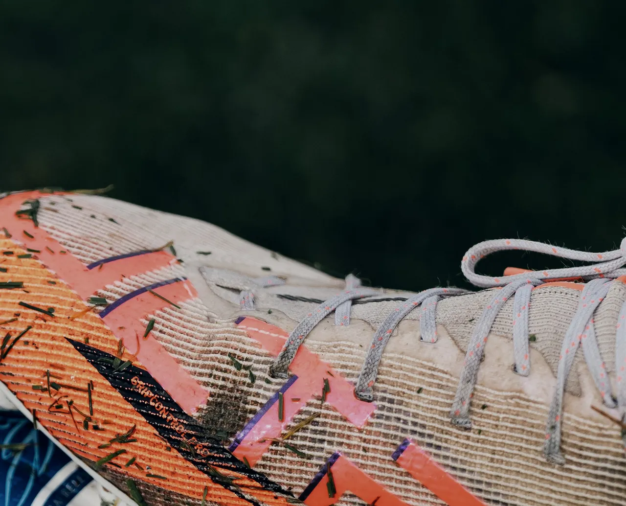 Detail of the ember-orange upper, scuffed from the pitch.