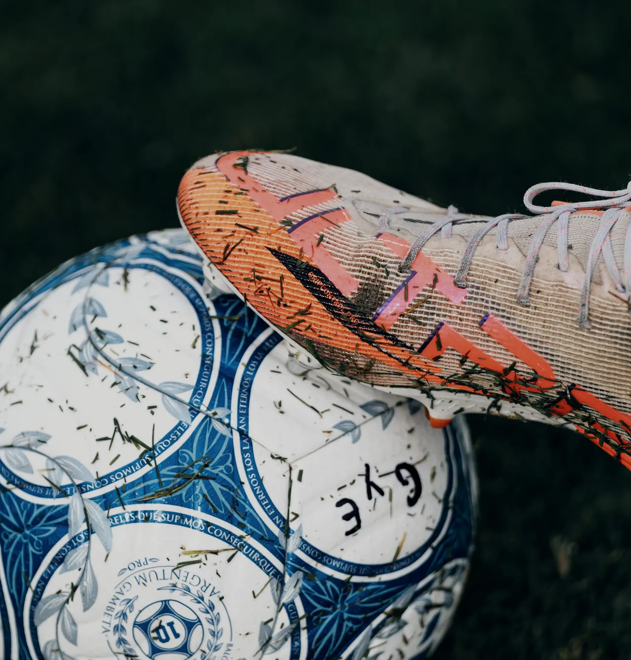 An ember-orange boot resting on top of a blue and white ball.