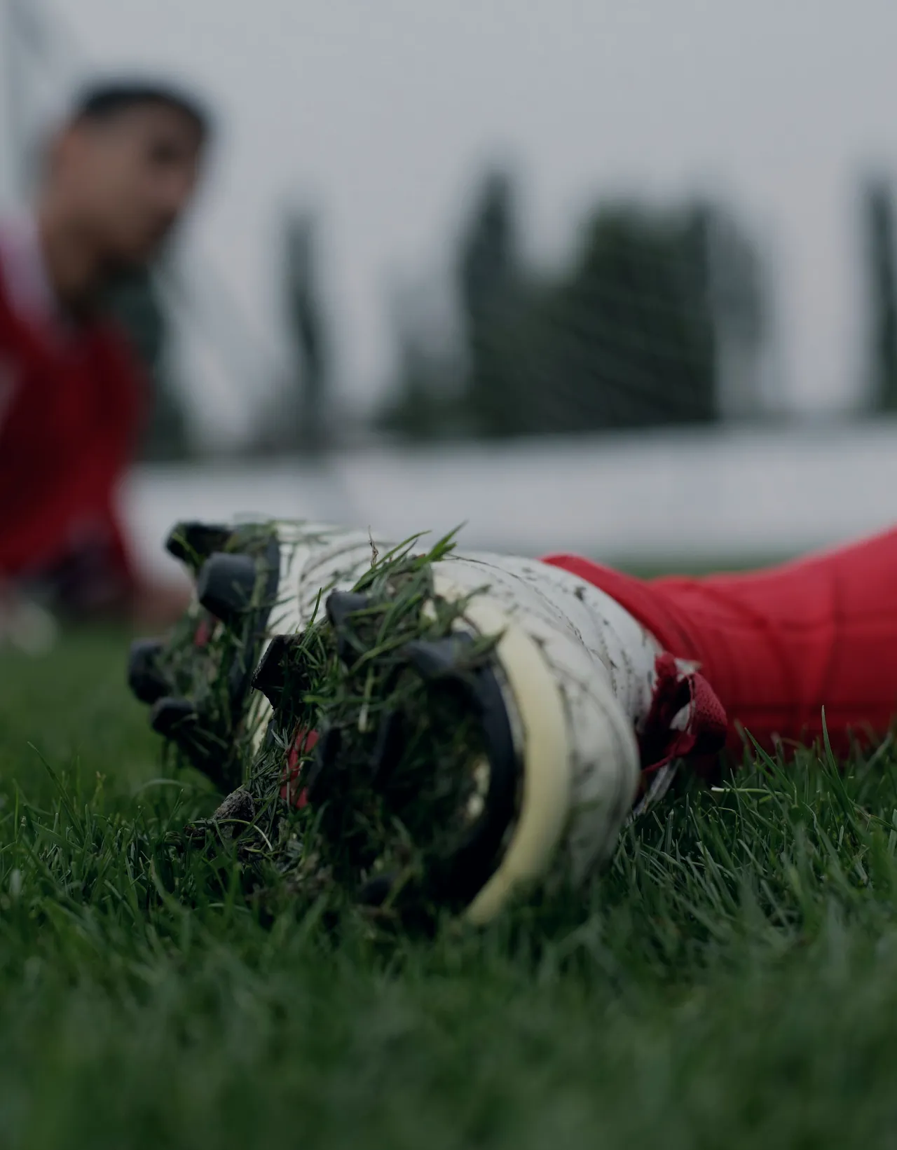 Close to the ground: a boot’s studs packed with torn grass after a slide.